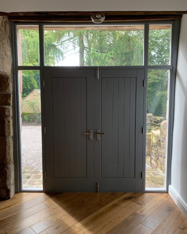 Interior view of charcoal French doors with sidelights and transom in room with exposed beams