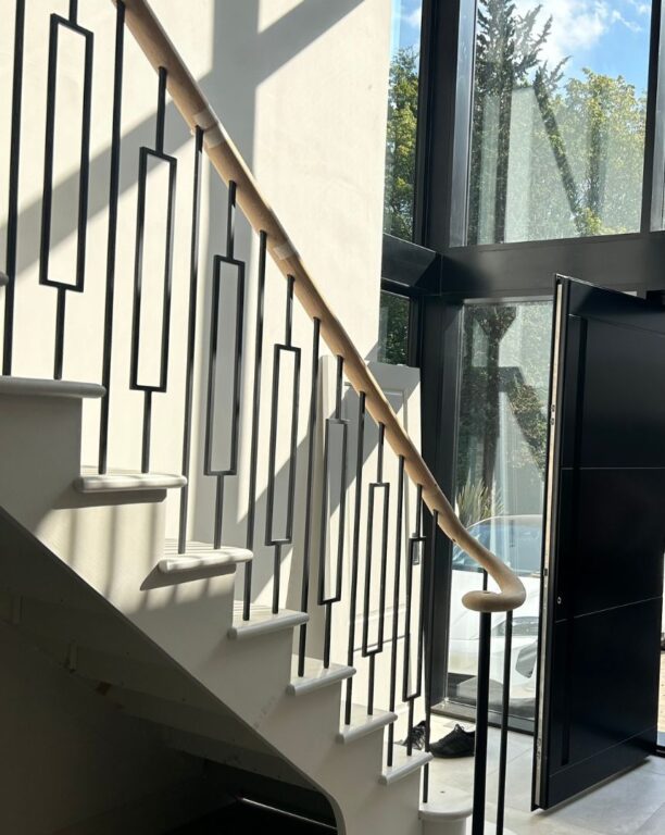 Modern staircase with white treads and geometric black metal balustrade by Overgreen Joinery