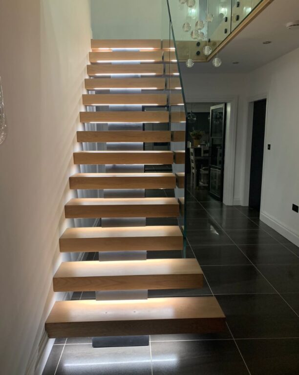 Modern floating oak staircase with glass balustrade and contemporary pendant lighting by Overgreen Joinery