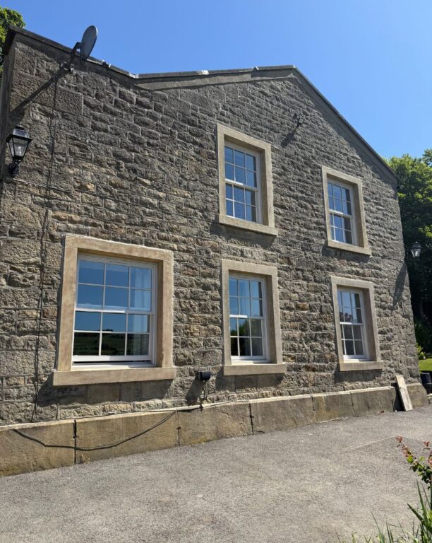 Multiple Georgian sash windows with stone surrounds on traditional two-story stone building
