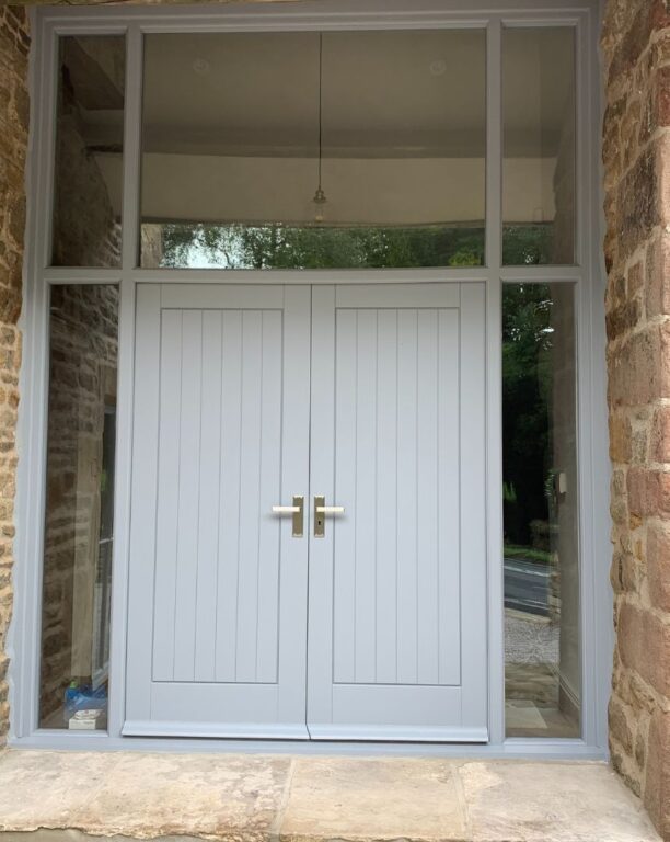 Grey French doors with full glazed surround including sidelights and fanlight in stone cottage
