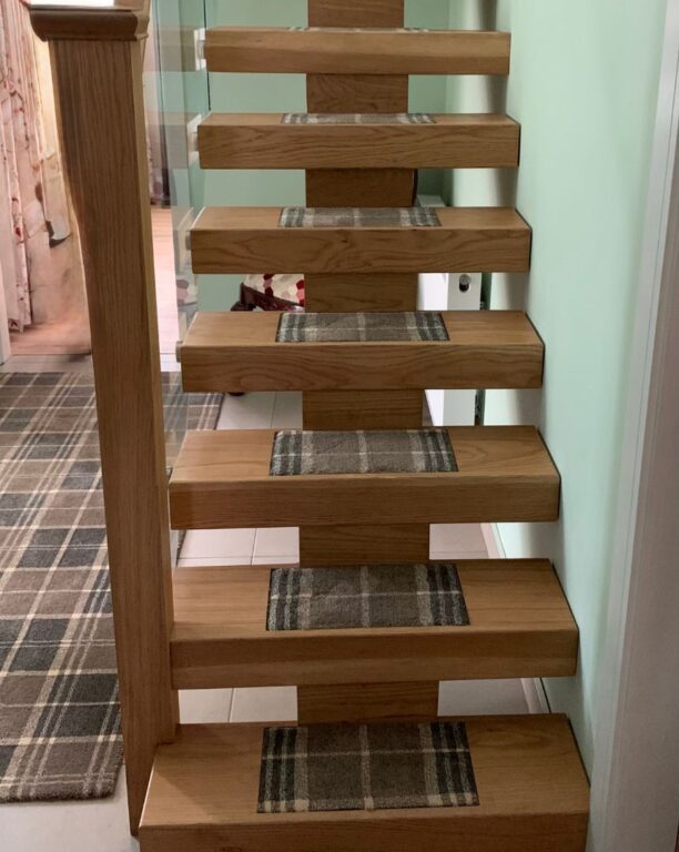 Custom oak floating staircase with grey tartan carpet runners and glass balustrade by Overgreen Joinery