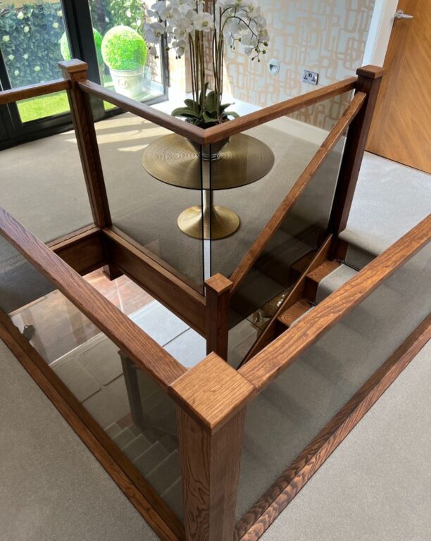 Oak staircase landing with glass panel balustrade and modern interior design by Overgreen Joinery