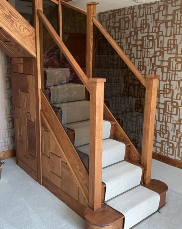 Oak staircase with decorative geometric side panels and cream carpet runner by Overgreen Joinery