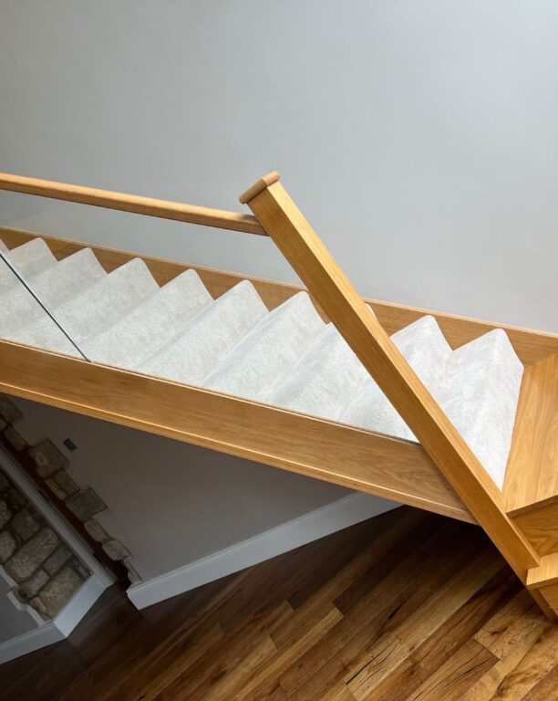 Oak staircase with glass panel balustrade and protective covering during installation by Overgreen Joinery