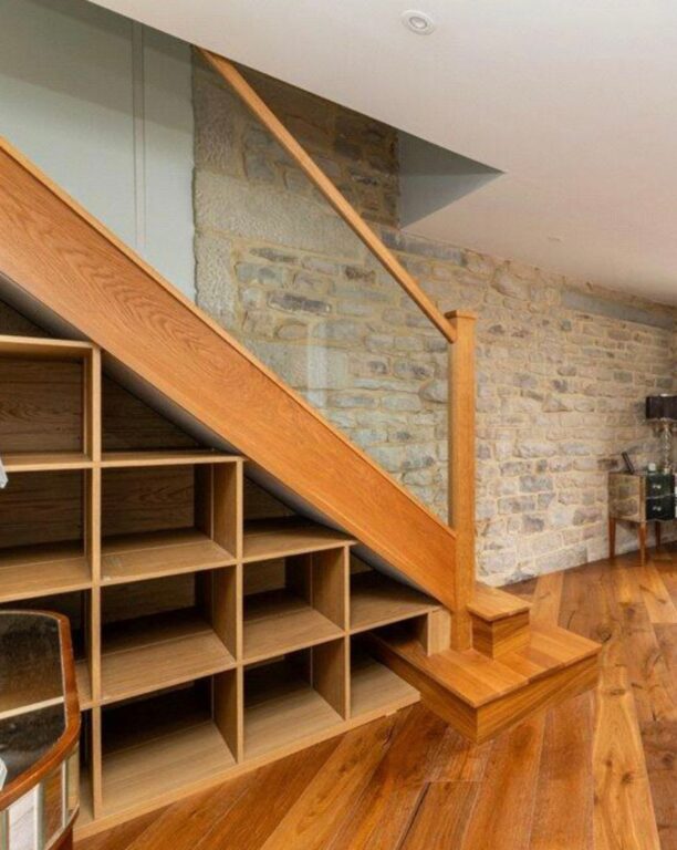 Custom oak staircase with glass balustrade and built-in understair storage shelving by Overgreen Joinery