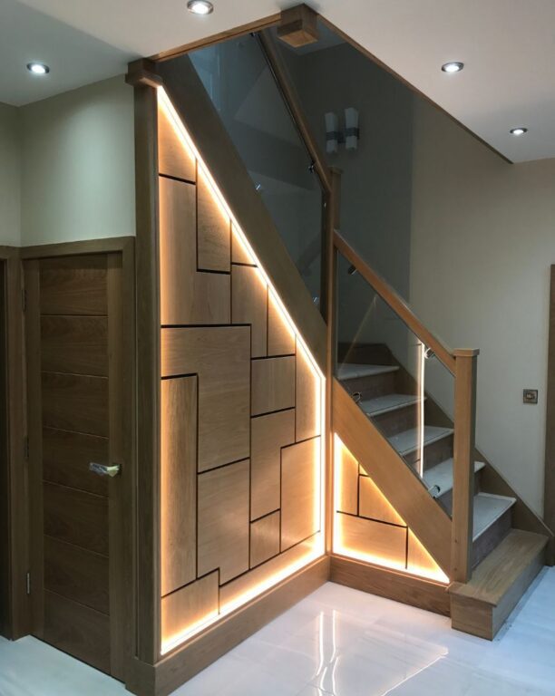 Modern oak staircase with integrated LED lighting, glass balustrade and bespoke understair storage by Overgreen Joinery