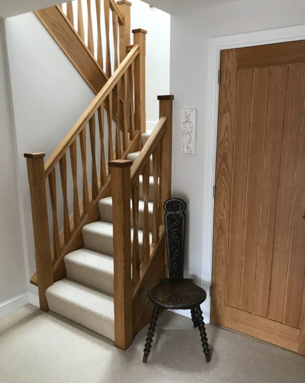 Traditional oak staircase with spindle balustrade and cream carpet runner by Overgreen Joinery