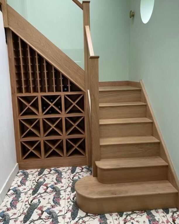 Oak staircase with integrated wine storage rack and curved bottom steps by Overgreen Joinery