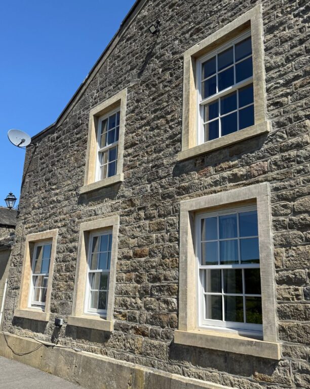 Traditional sash windows with stone lintels on upper floors of period stone building
