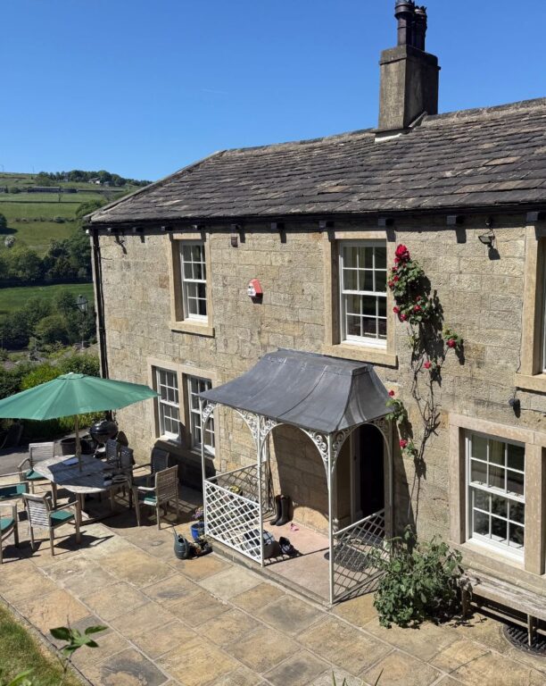 Traditional stone house with period sash windows across multiple levels and patio area