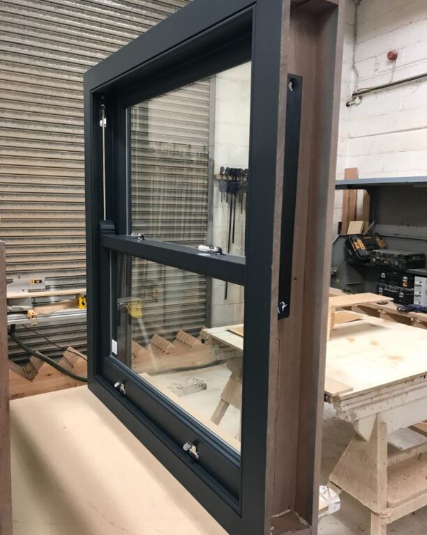 Dark green sash window frame in manufacturing workshop showing traditional craftsmanship
