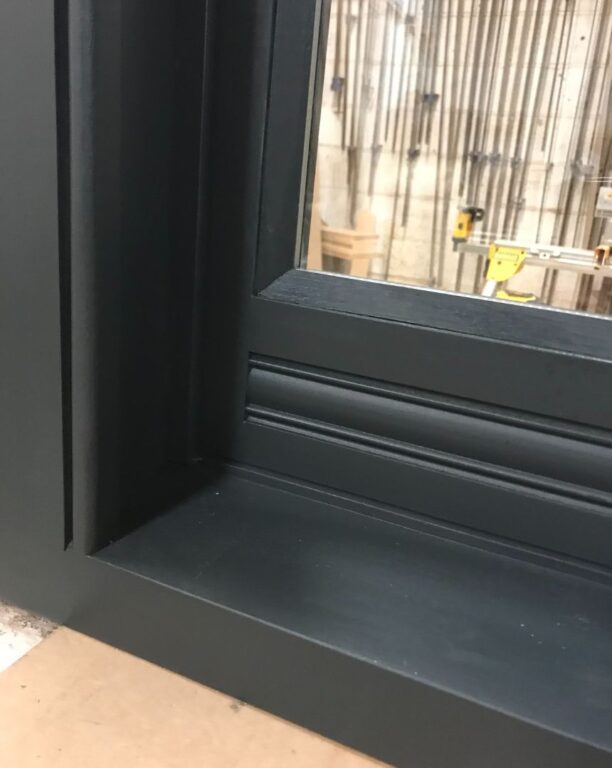 Close-up detail of dark green sash window sill showing traditional profile and finish