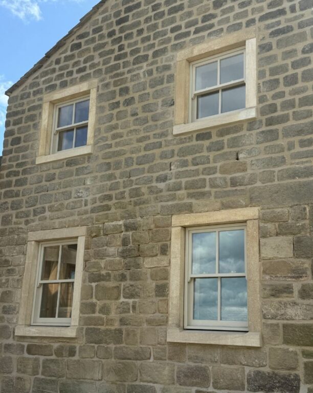 Grey French doors with full glazed surround including sidelights and fanlight in stone cottage