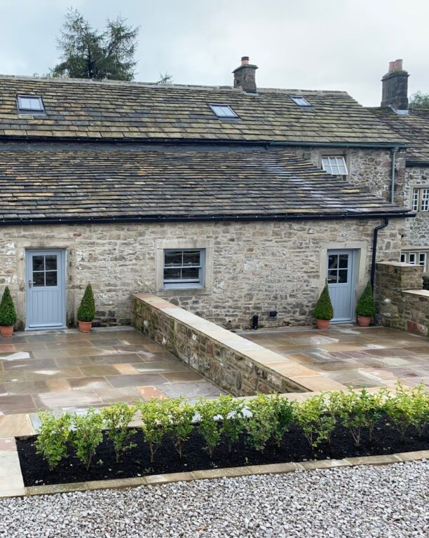 Stone cottage conversion with grey doors and windows featuring traditional slate roof