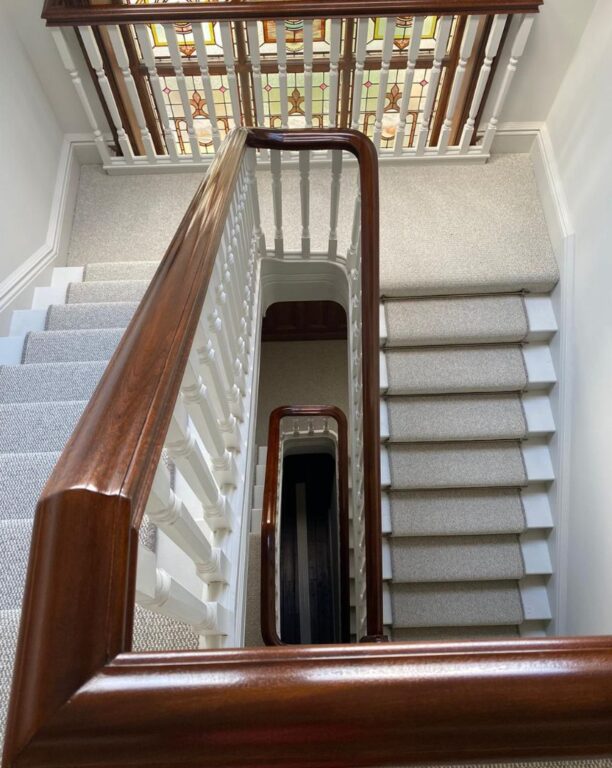 Traditional mahogany staircase with ornate stained glass window and white painted spindles by Overgreen Joinery