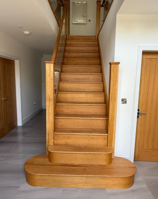 Traditional oak staircase with curved bottom steps and solid wood handrail by Overgreen Joinery