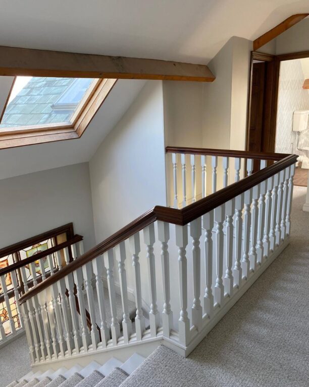 Traditional staircase with white painted spindles and mahogany handrail in loft conversion by Overgreen Joinery