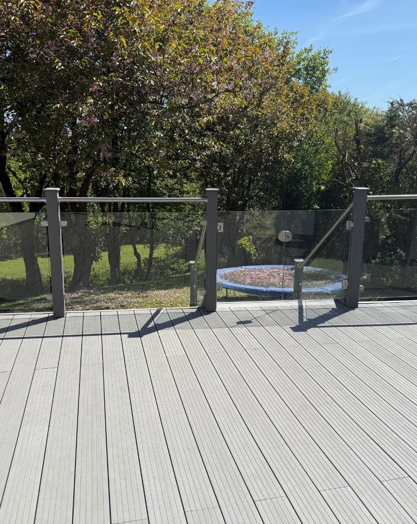 Modern composite decking with glass panel balustrade overlooking garden area