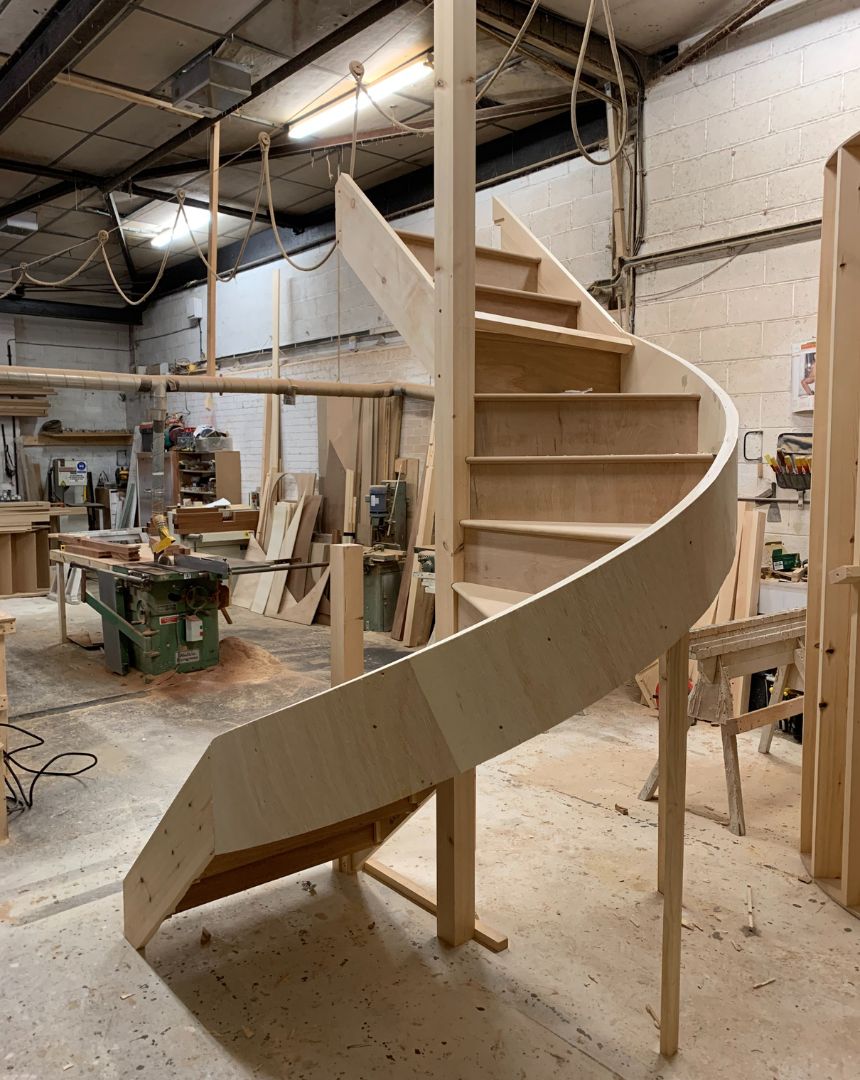 Curved wooden staircase being manufactured in joinery workshop showing craftsmanship process