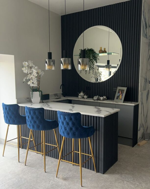 Contemporary kitchen island with dark fluted panel cladding and marble effect worktop